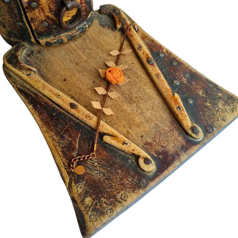 A handmade bracelet featuring a single orange rose with brown needle lace leaves on a brown band, made with artificial silk thread using the traditional Turkish Oya technique.